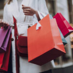 Elegant young woman with shopping bags standing on the street